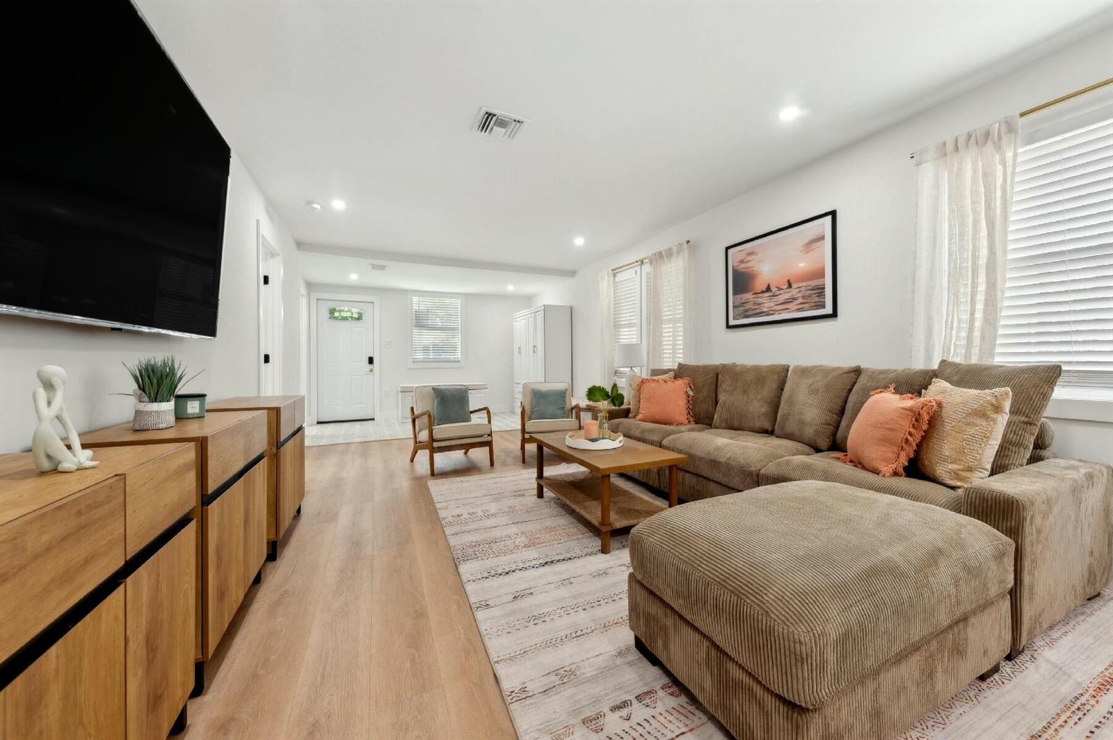 A living room features a brown sectional sofa, wooden media console, and light wood flooring — 125 NW 3rd Avenue, Delray Beach FL 33444, DELRAY BEACH, FL