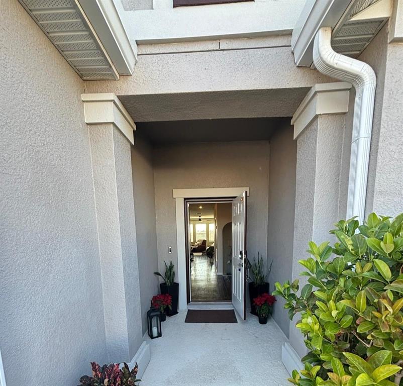 A covered entryway leads to an open front door revealing a view into the home — 1929 HEART LAKE DRIVE, GROVELAND, FL