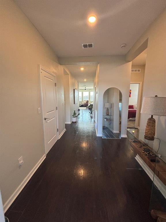 A long hallway with dark wood floors leads toward a living area with large windows — 1929 HEART LAKE DRIVE, GROVELAND, FL