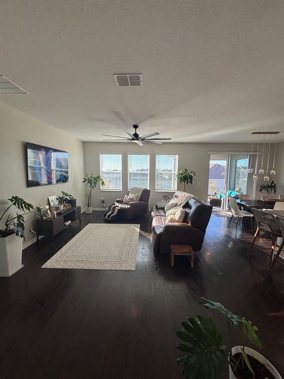 A living room features dark hardwood floors, a ceiling fan, and a brown leather sofa — 1929 HEART LAKE DRIVE, GROVELAND, FL
