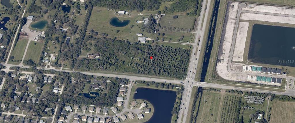 An aerial view shows a wooded lot marked with a red pin near a road — 5992 8TH STREET, VERO BEACH, FL