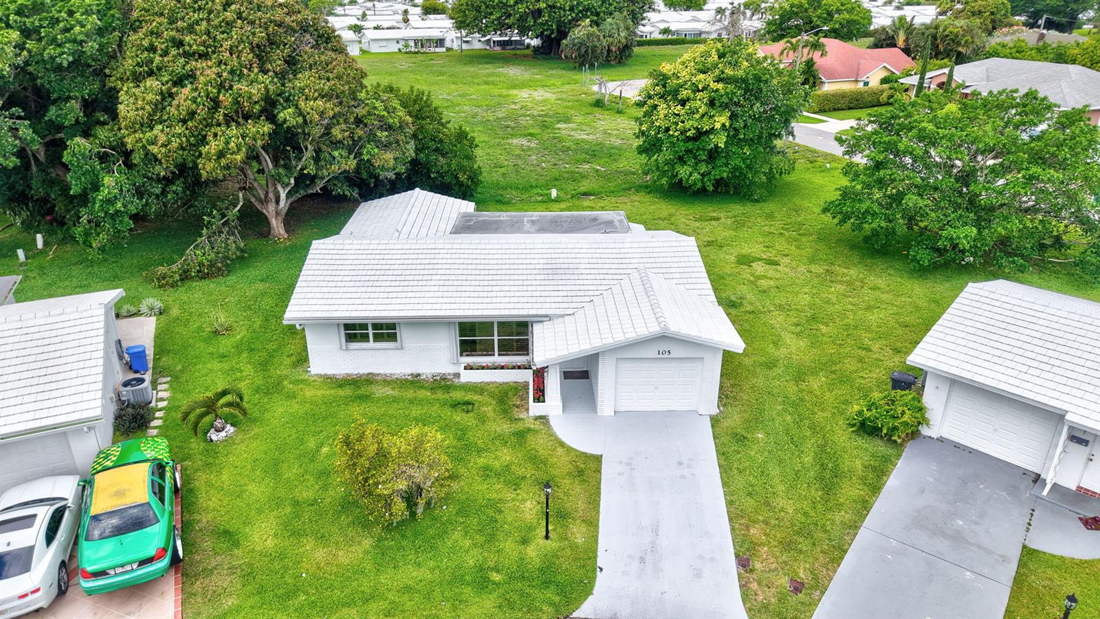 An aerial view shows a white single-story house with a garage and a green lawn — 105 NW 8th Place, Boynton Beach FL 33426, BOYNTON BEACH, FL