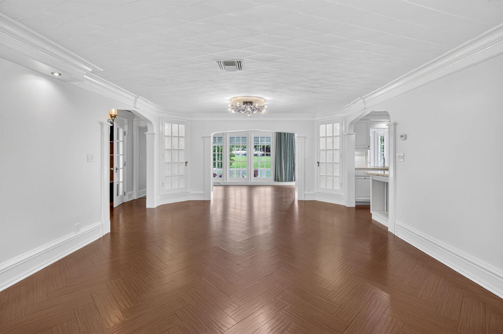 A spacious, empty room features herringbone wood floors, white walls, and a patterned ceiling — 105 NW 8th Place, Boynton Beach FL 33426, BOYNTON BEACH, FL