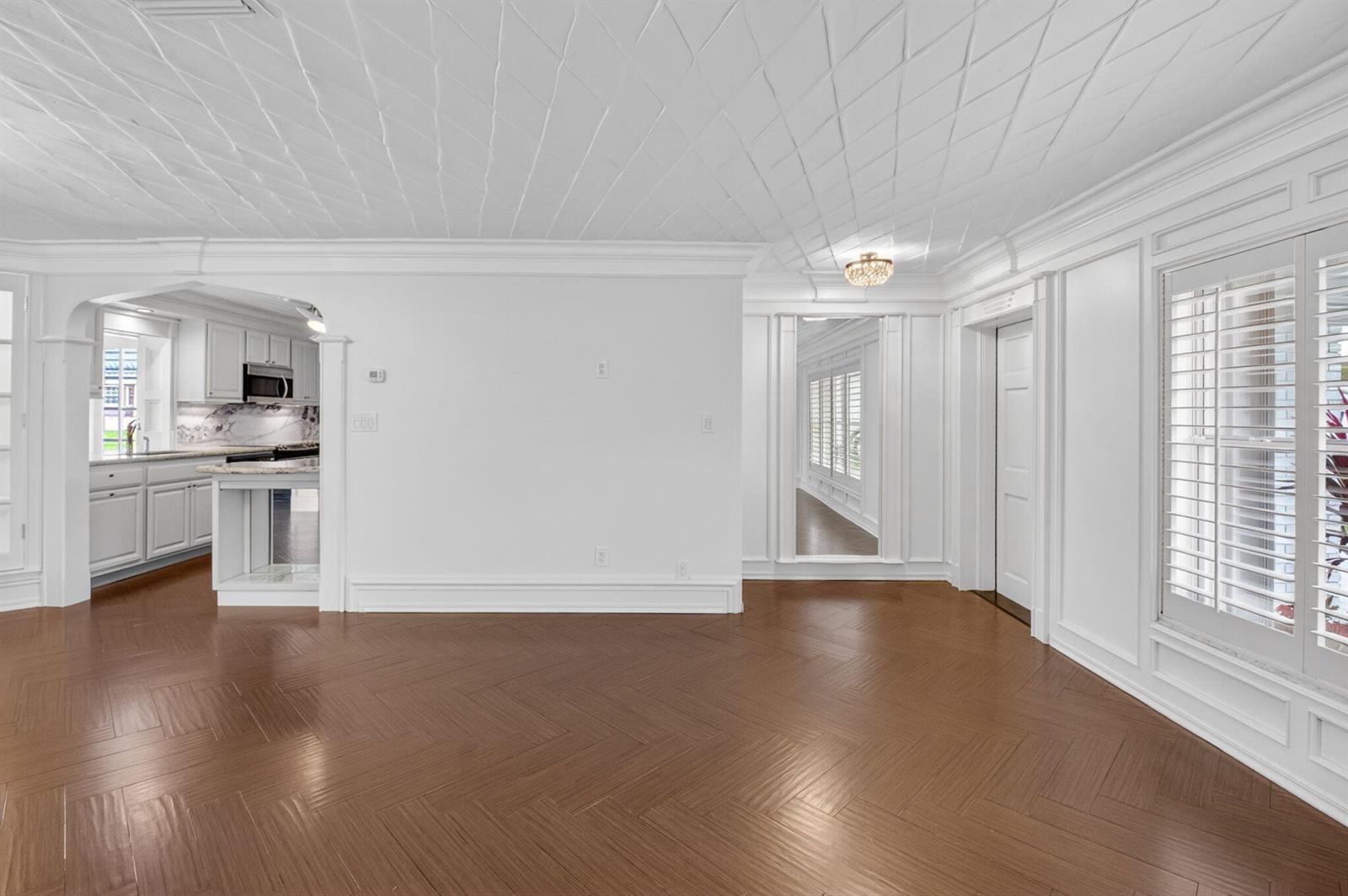 An empty room with herringbone wood floors, white paneled walls, and a textured ceiling — 105 NW 8th Place, Boynton Beach FL 33426, BOYNTON BEACH, FL