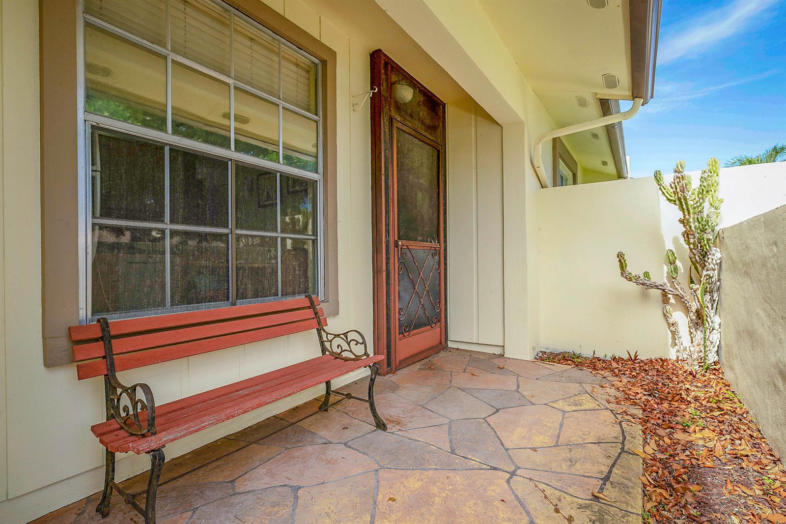 A patio with a stone floor, a red bench, and a cactus against a wall — 5231 Copperleaf Circle, Delray Beach FL 33484, DELRAY BEACH, FL