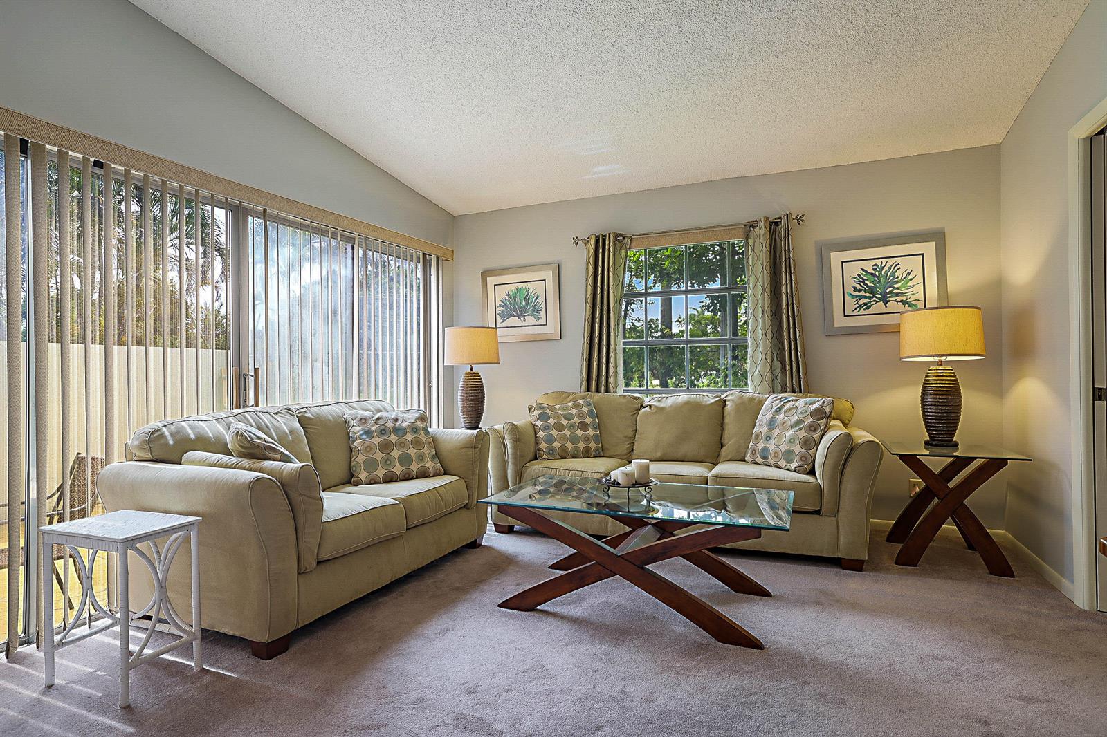 A living room features two beige sofas, a glass coffee table, and large sliding glass doors — 5231 Copperleaf Circle, Delray Beach FL 33484, DELRAY BEACH, FL