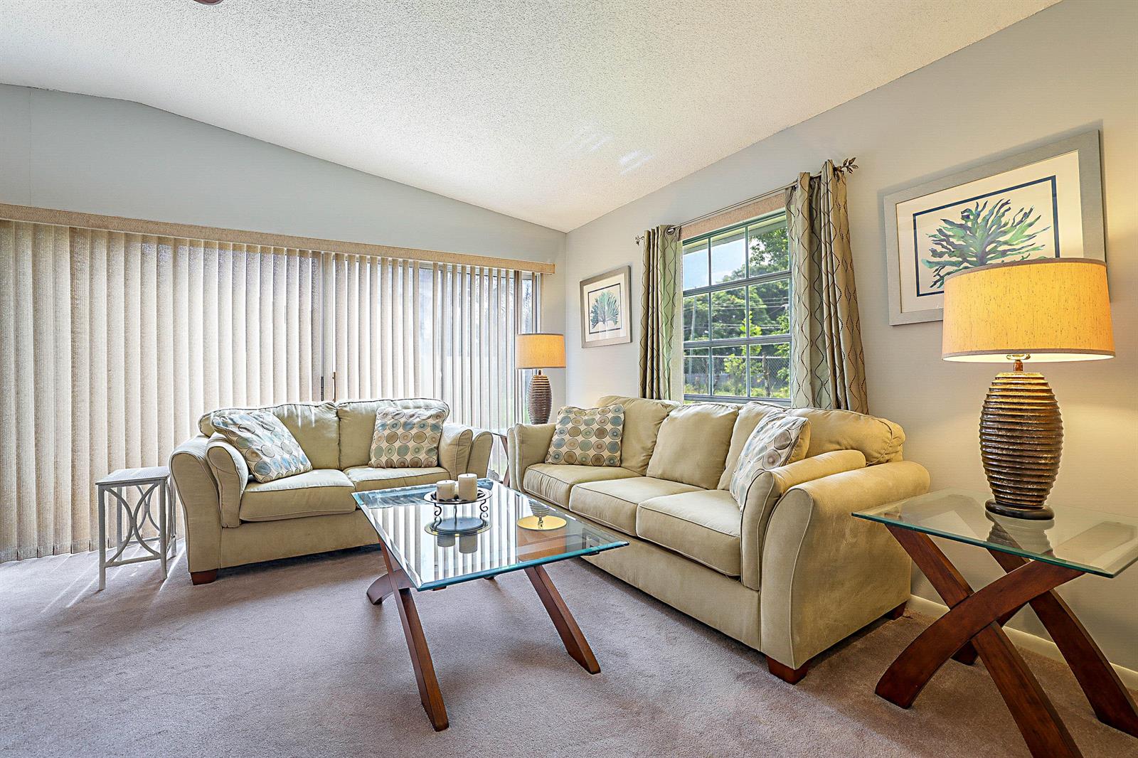A living room features two beige sofas, a glass coffee table, and a glass side table — 5231 Copperleaf Circle, Delray Beach FL 33484, DELRAY BEACH, FL