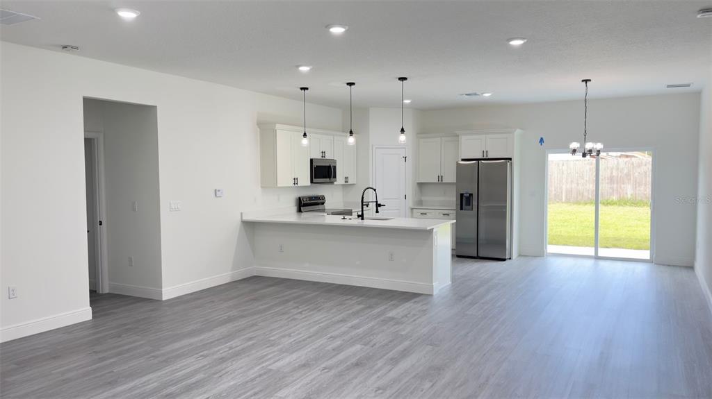 A modern kitchen features white cabinets, stainless steel appliances, and a breakfast bar island — 9848 N CORTLANDT DRIVE, CITRUS SPRINGS, FL