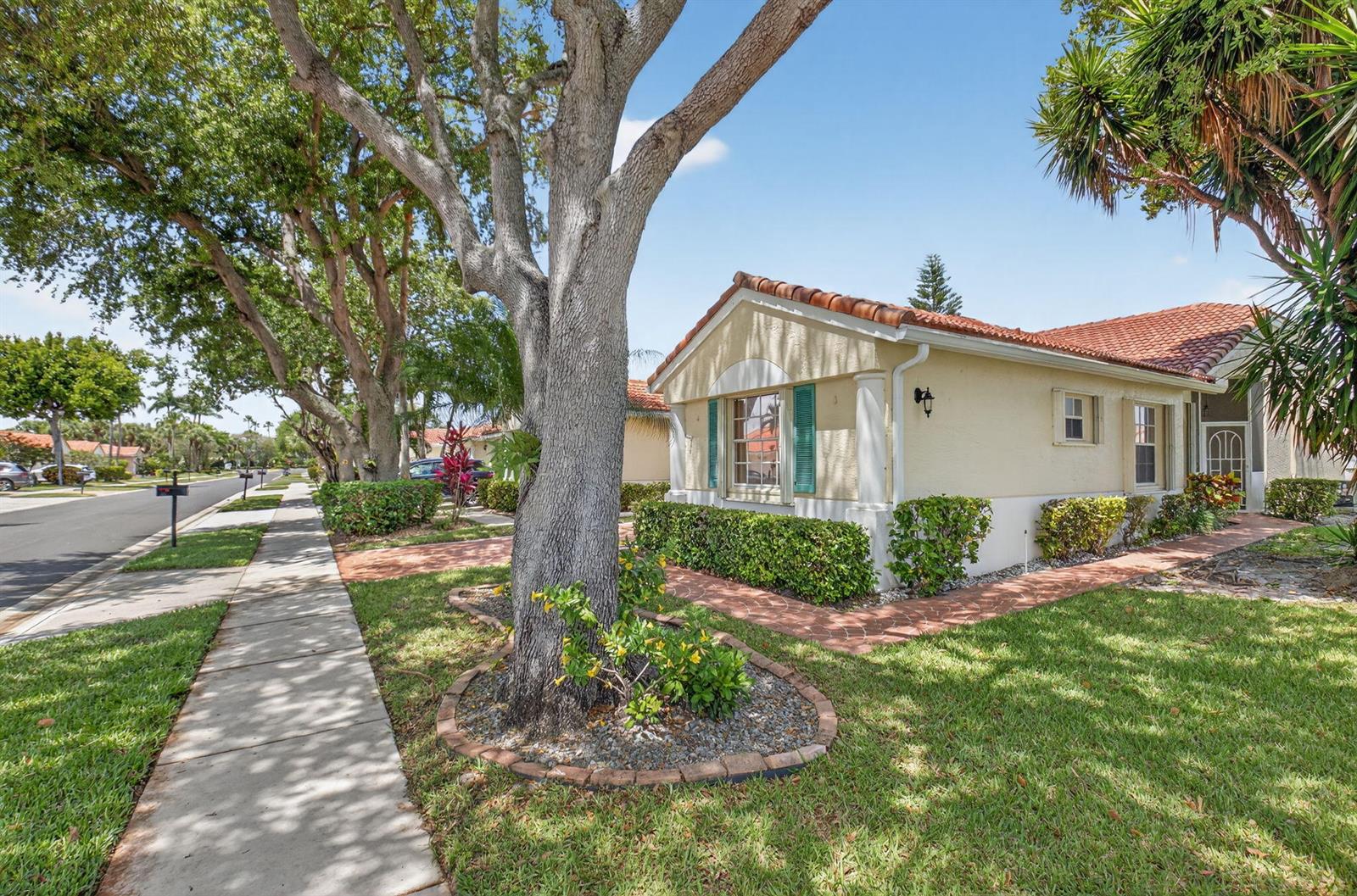 A single-story house with a tile roof and green shutters sits beside a sidewalk — 6171 Floral Lakes Drive, Delray Beach FL 33484, DELRAY BEACH, FL