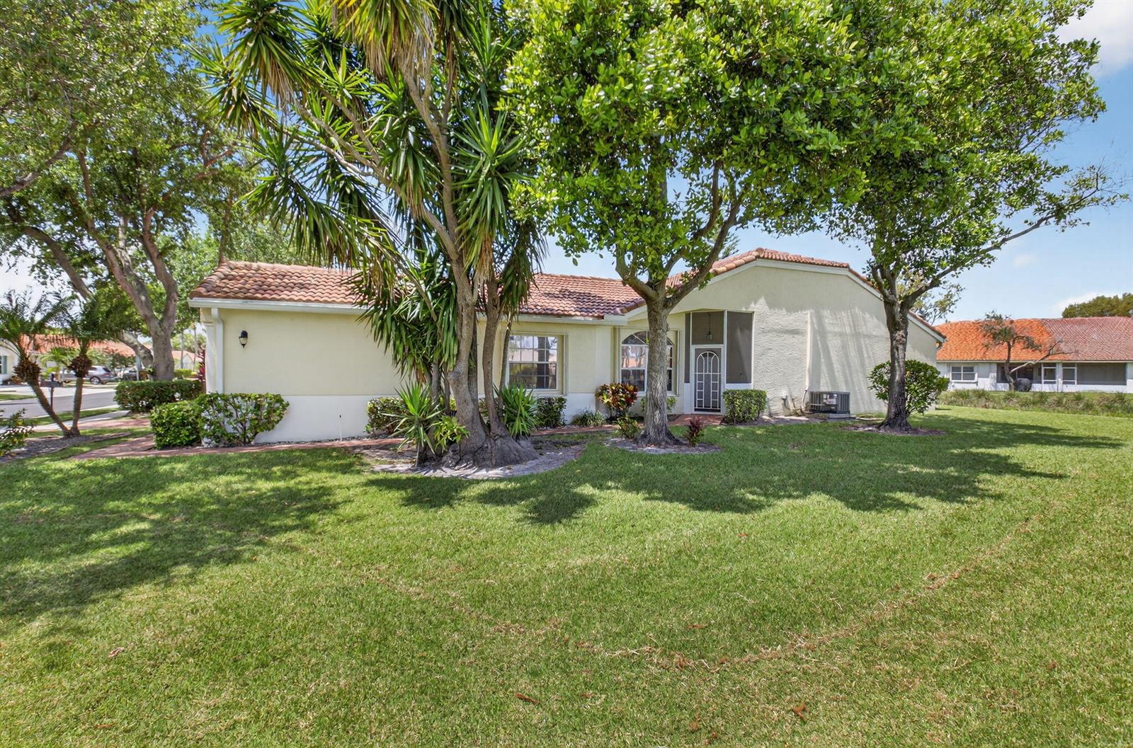 A single-story house with a tile roof, light-colored stucco walls, and mature trees in front — 6171 Floral Lakes Drive, Delray Beach FL 33484, DELRAY BEACH, FL