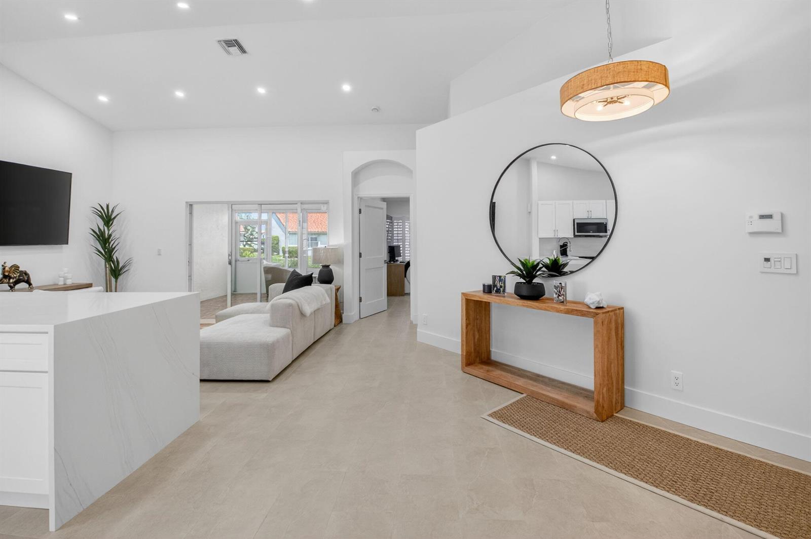 A bright, open-concept living area features a white kitchen island, a console table, and tile flooring — 6171 Floral Lakes Drive, Delray Beach FL 33484, DELRAY BEACH, FL