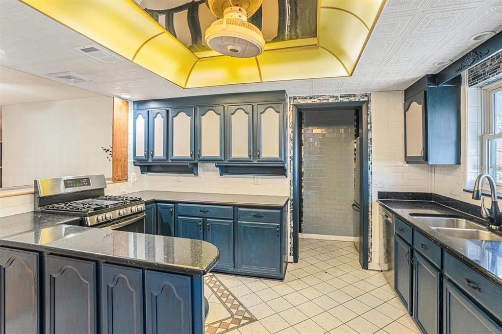 A kitchen with dark blue cabinets, black countertops, white subway tile, and a yellow ceiling — 1900 59TH AVENUE N UNIT 210, ST PETERSBURG, FL