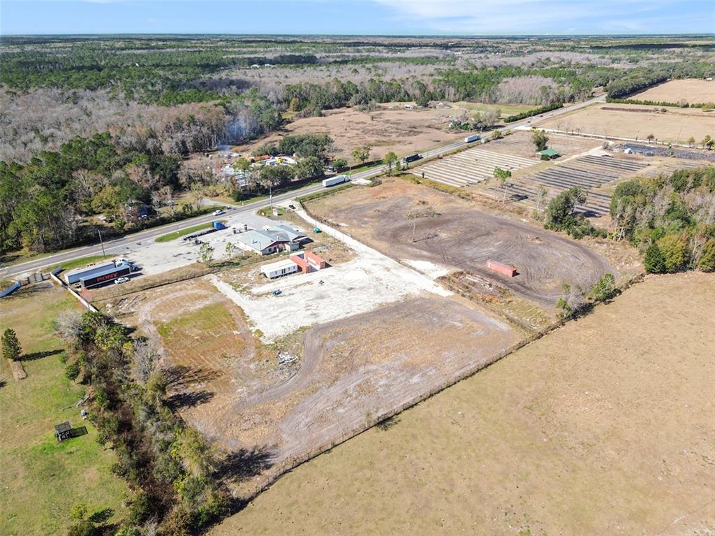 An aerial view shows a commercial property with a building, parking area, and surrounding land — 3824 STATE ROAD 33, CLERMONT, FL