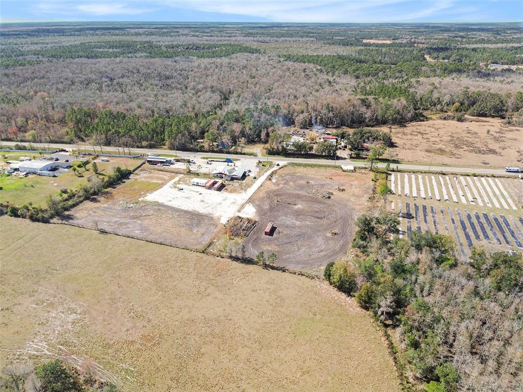An aerial view shows a rural property with cleared land, a building, and surrounding woods — 3824 STATE ROAD 33, CLERMONT, FL