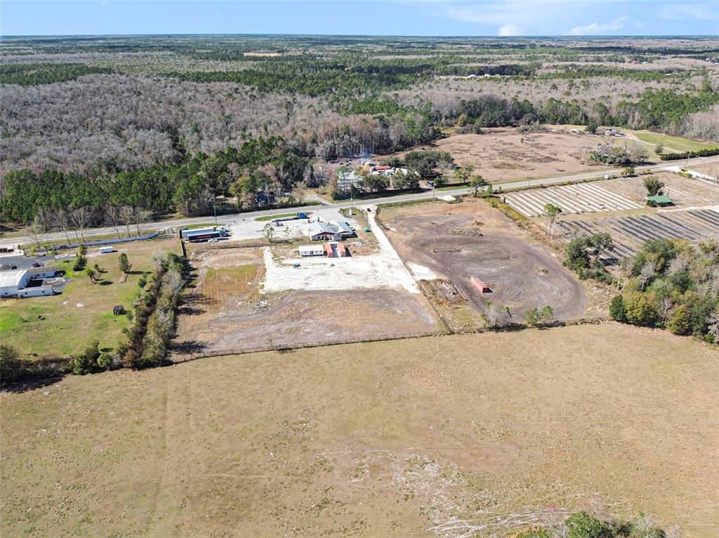 An aerial view shows a large, partially cleared lot with a building and surrounding fields — 3824 STATE ROAD 33, CLERMONT, FL