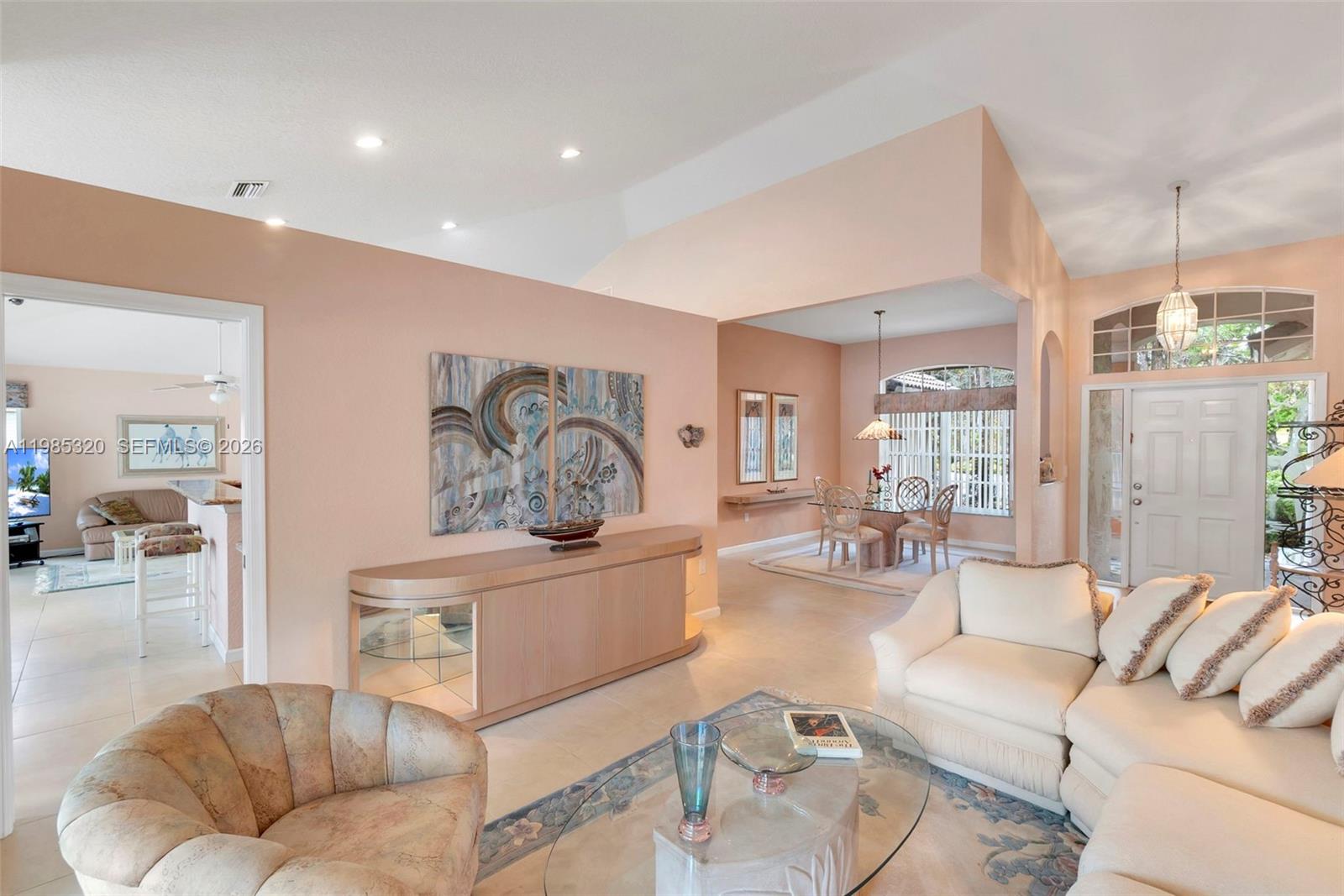 A living room and dining area with peach walls, tile floors, and vaulted ceilings — 4927 NW 67th Ave, Lauderhill FL 33319, LAUDERHILL, FL