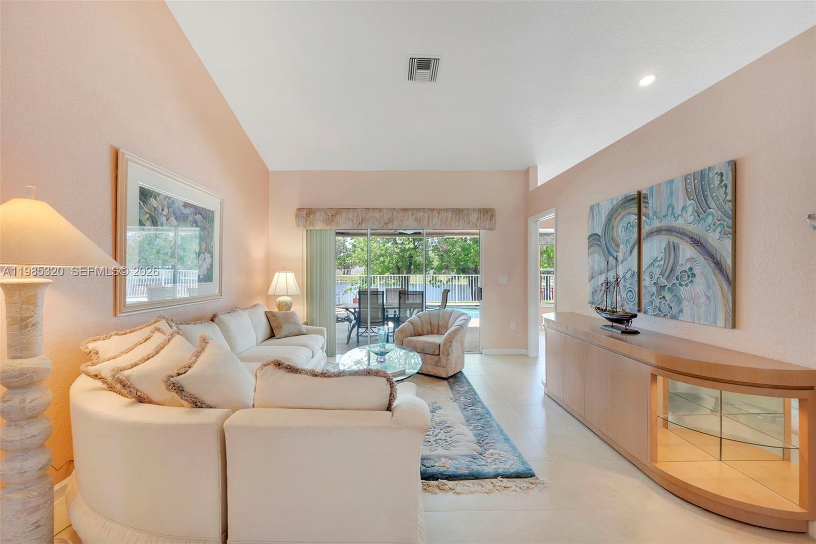 A living room features a white sectional sofa, a glass coffee table, and sliding doors — 4927 NW 67th Ave, Lauderhill FL 33319, LAUDERHILL, FL