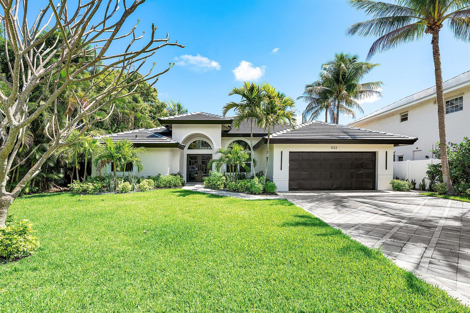 A single-story house with a dark tiled roof, white stucco walls, and a paved driveway — 1132 NE 3rd Avenue, Boca Raton FL 33432, BOCA RATON, FL