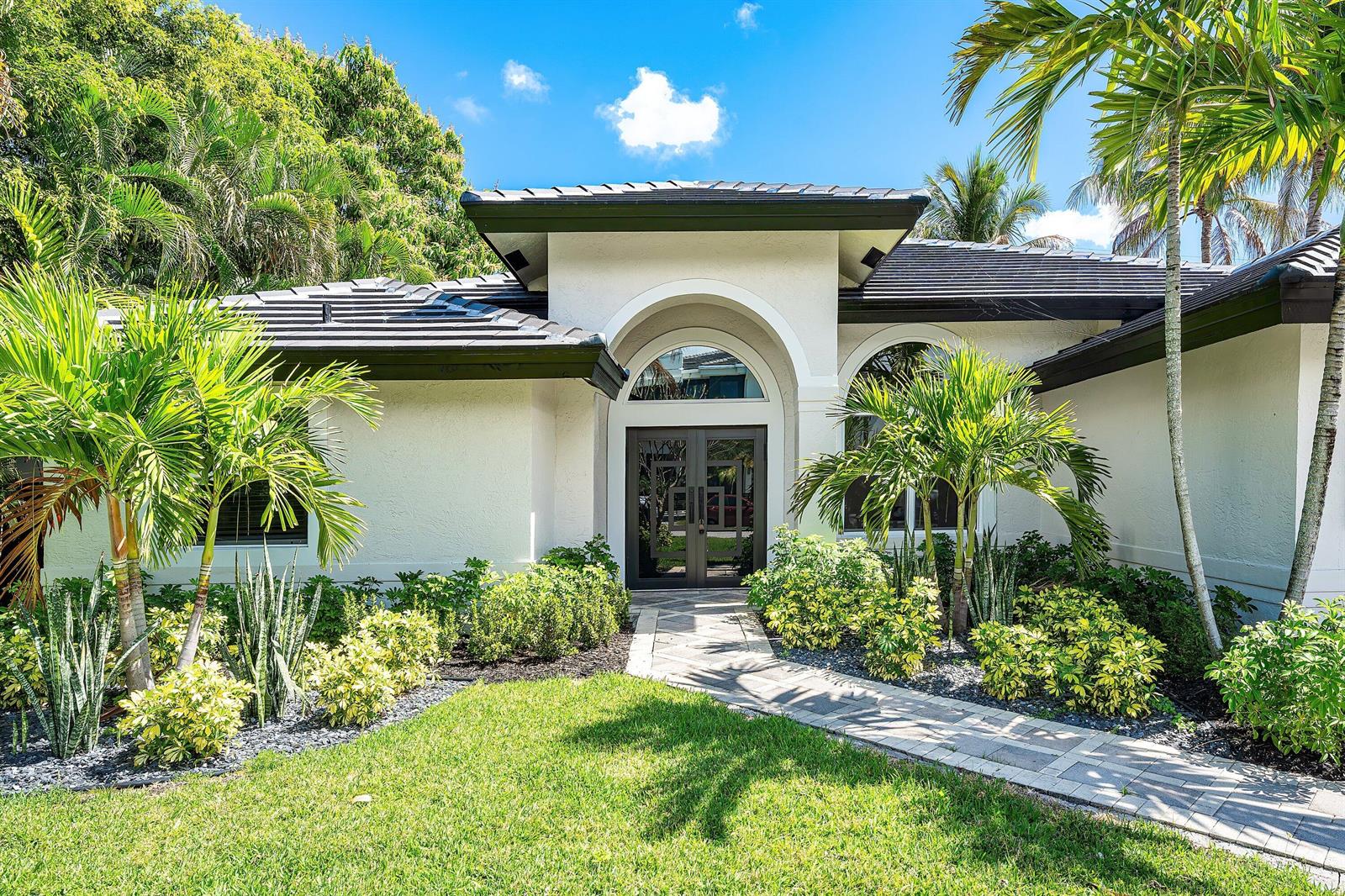 A white house with a dark tiled roof, arched entryway, and tropical landscaping — 1132 NE 3rd Avenue, Boca Raton FL 33432, BOCA RATON, FL