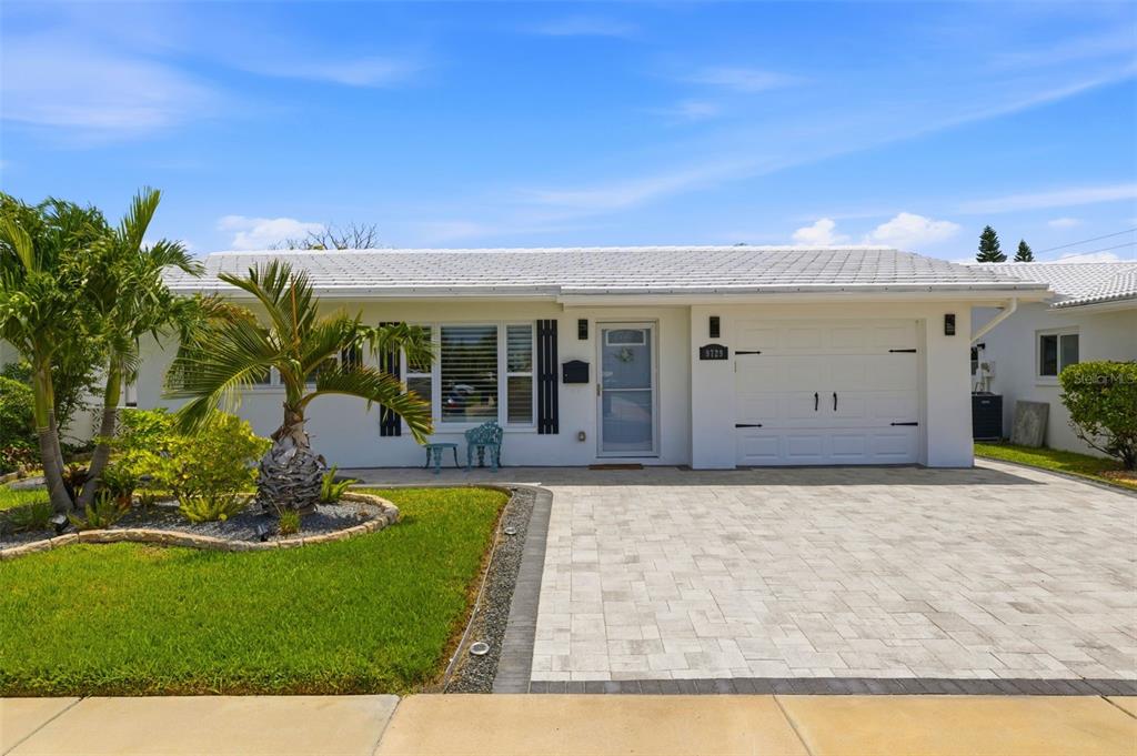 A single-story white house features a paved driveway, a garage, and a landscaped front yard — 9729 37TH STREET N, PINELLAS PARK, FL