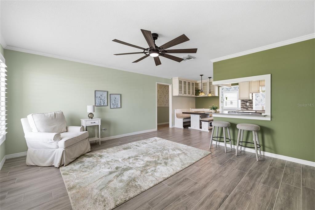 A living room with light green walls, a white armchair, and a breakfast bar area — 9729 37TH STREET N, PINELLAS PARK, FL