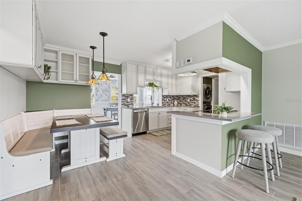 A kitchen with white cabinetry, a breakfast nook, and a peninsula with bar stools — 9729 37TH STREET N, PINELLAS PARK, FL