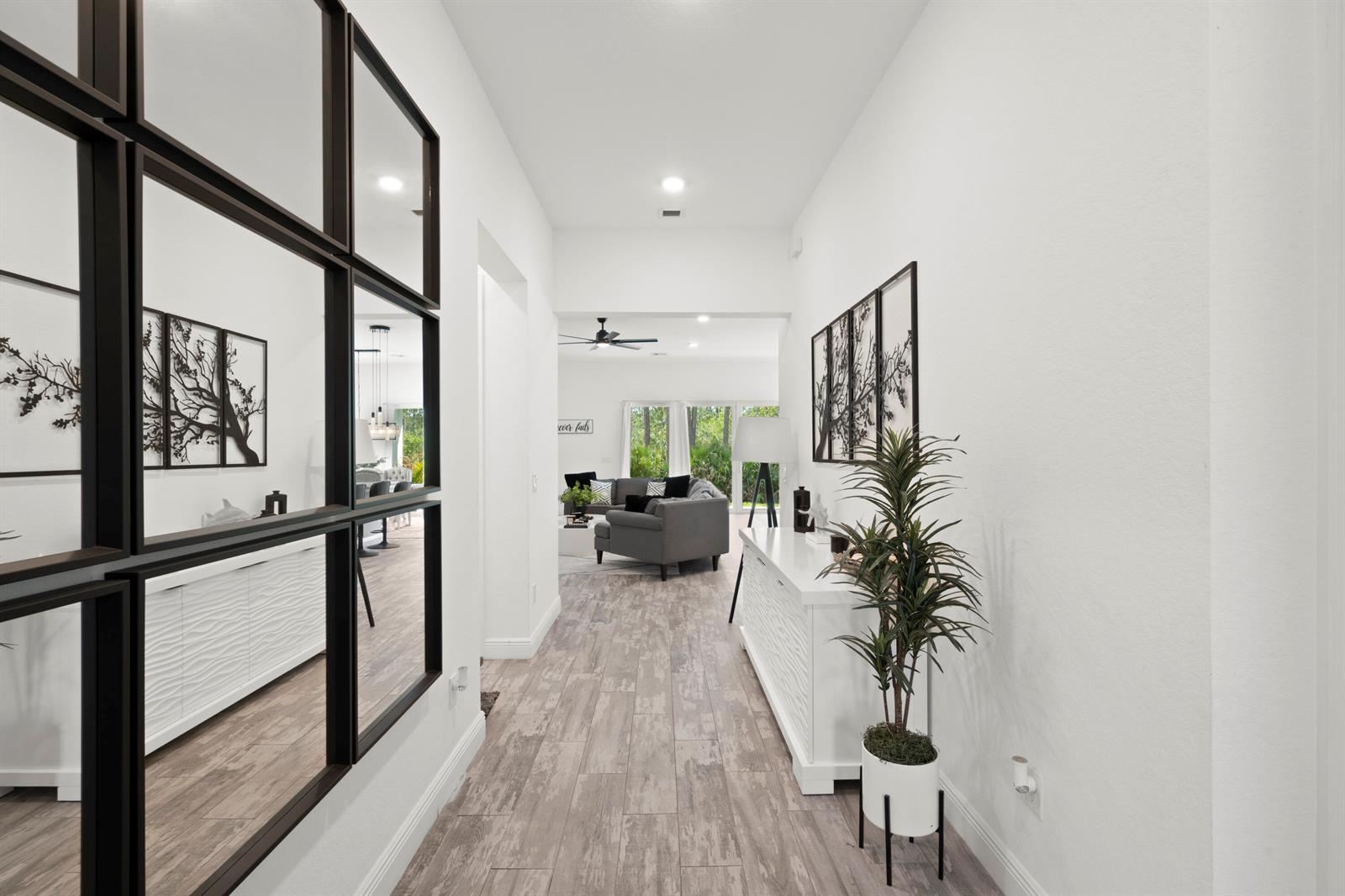 A bright hallway features wood-look tile flooring, a large grid mirror, and a white console table — 4630 SW Ardsley Drive, Stuart FL 34997, STUART, FL