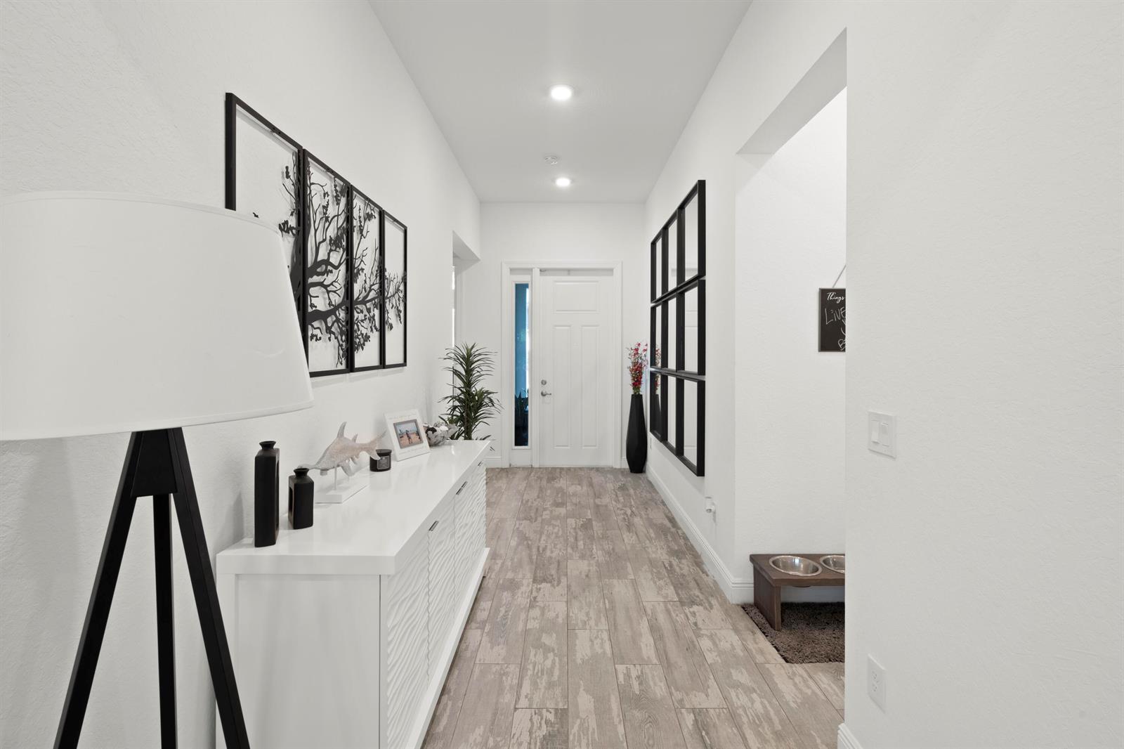 A bright entryway features white walls, wood-look tile flooring, a console table, and wall art — 4630 SW Ardsley Drive, Stuart FL 34997, STUART, FL