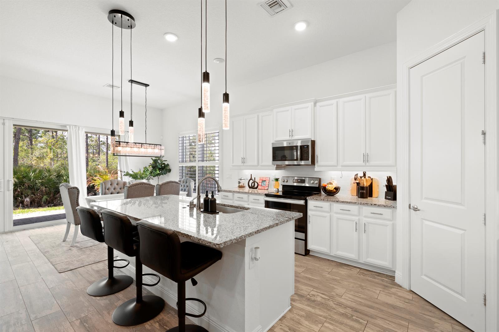 A modern kitchen features white cabinets, granite countertops, a central island, and barstool seating — 4630 SW Ardsley Drive, Stuart FL 34997, STUART, FL