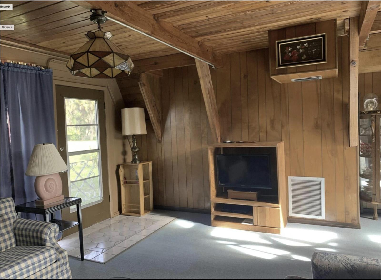 A living room features wood-paneled walls, a vaulted wood ceiling, and a television console — 31110 U.s. 441, Okeechobee FL 34972, OKEECHOBEE, FL