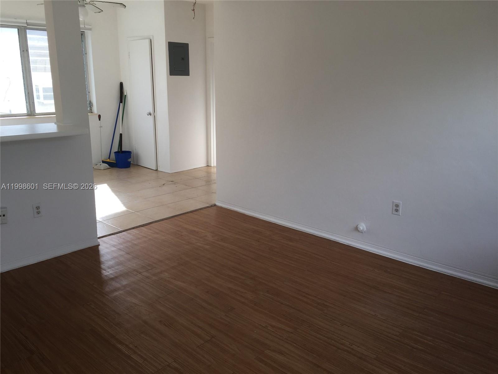 An interior view shows a room with wood-look flooring, white walls, and an adjacent tiled area — 4740 Pine Tree Dr # 26, Miami Beach FL 33140, MIAMI BEACH, FL