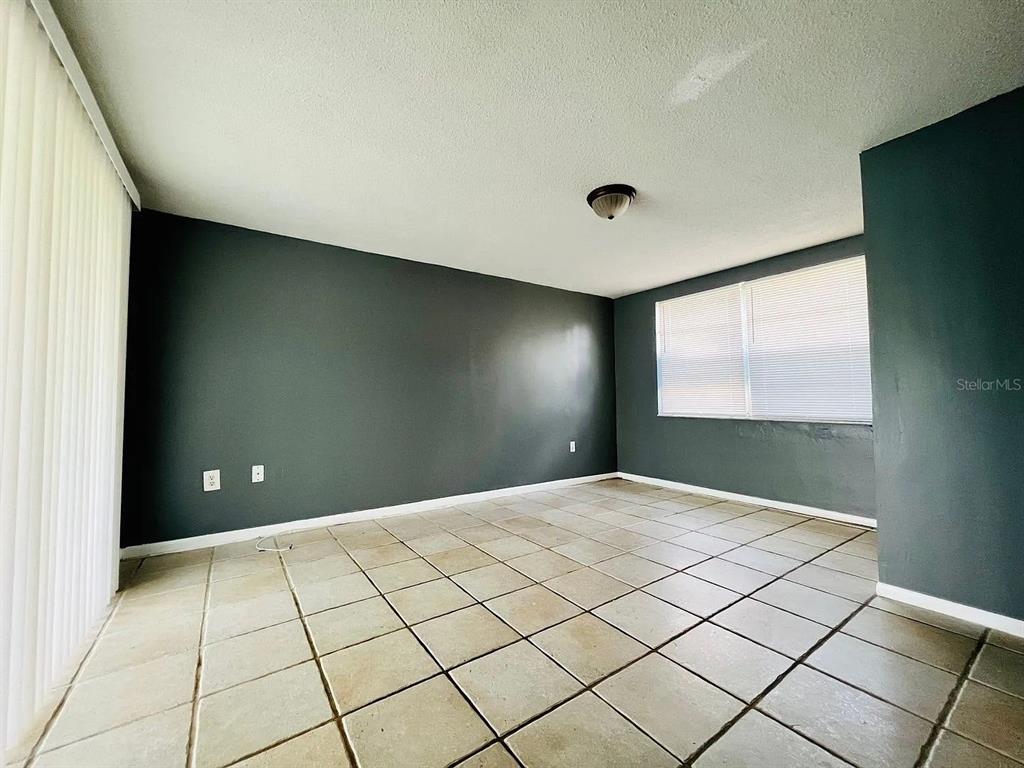 An empty room features dark gray walls, light-colored tile flooring, and a sliding glass door — 7907 YUCCA DRIVE, NEW PORT RICHEY, FL