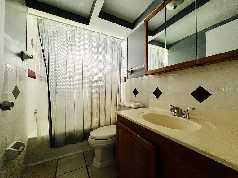 A bathroom features a vanity with a sink, a toilet, and a shower with curtains — 7907 YUCCA DRIVE, NEW PORT RICHEY, FL