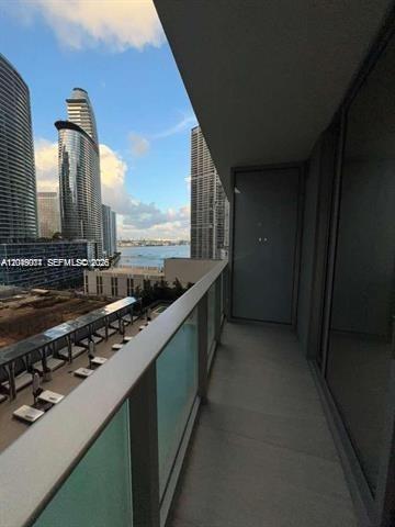 A balcony with a glass railing overlooks a city skyline and a body of water — 77 SE 5th St # 1704, Miami FL 33131, MIAMI, FL