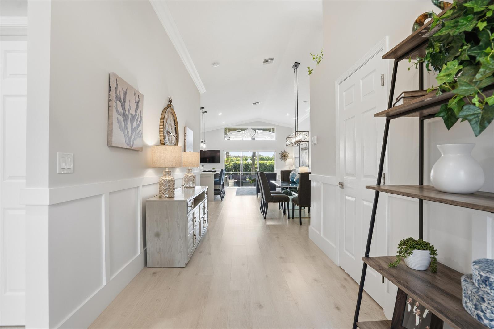 A bright hallway with light wood flooring leads into an open-concept dining and living area — 7348 Trentino Way, Boynton Beach FL 33472, BOYNTON BEACH, FL