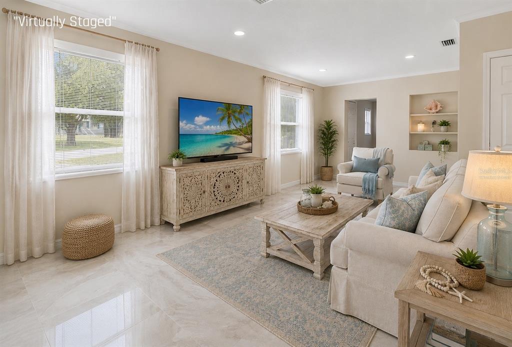 A living room with tile floors, a television on a wooden console, and neutral furniture — 1407 CORAL RIDGE DRIVE, PUNTA GORDA, FL