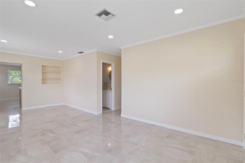 A bright, empty room features light-colored tile floors, recessed lighting, and built-in wall shelves — 1407 CORAL RIDGE DRIVE, PUNTA GORDA, FL