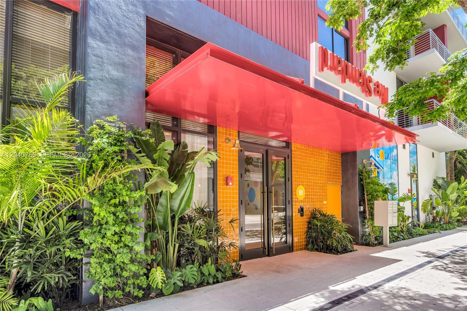 The exterior entrance of a building features a red awning over a yellow tiled wall — 90 NE 32nd, Miami FL 33127, MIAMI, FL