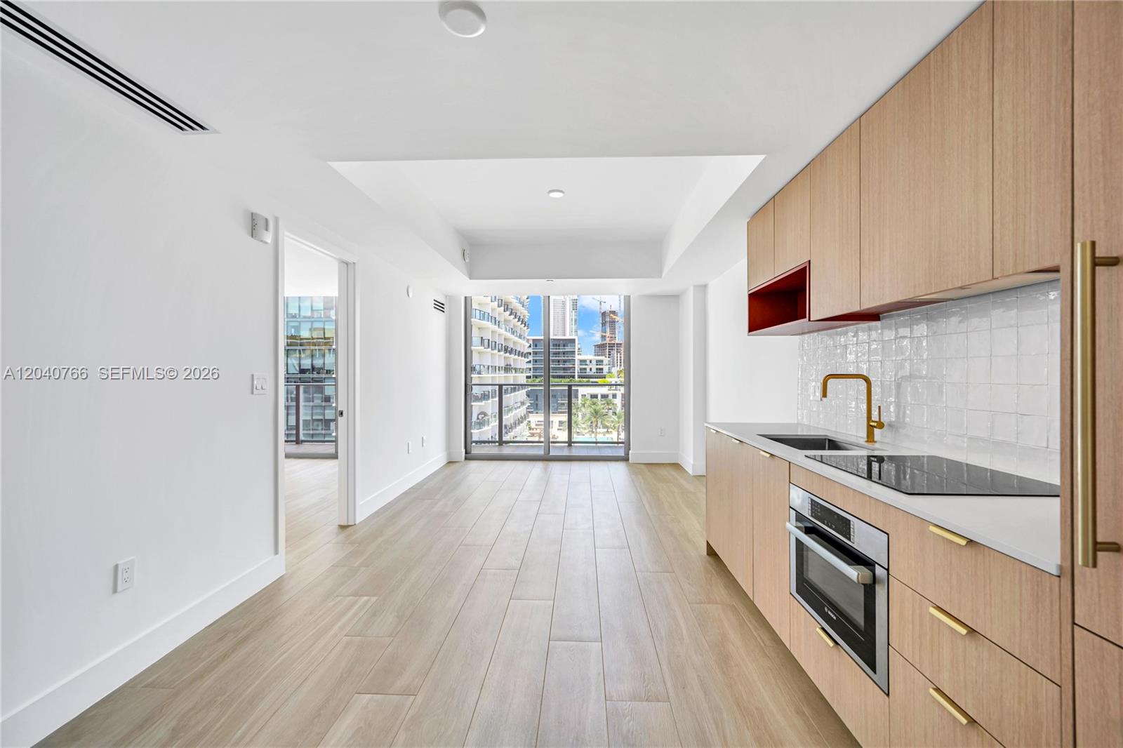 A modern kitchen features light wood cabinets, a white tile backsplash, and a balcony view — 90 NE 32nd, Miami FL 33127, MIAMI, FL