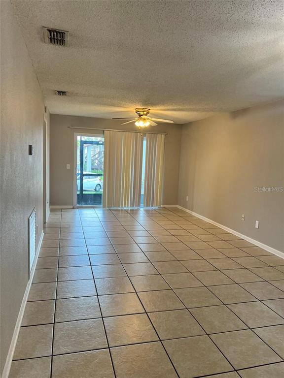 A living room with light-colored tile flooring, a ceiling fan, and sliding glass doors — 39132 COUNTY ROAD 54 UNIT 2246, ZEPHYRHILLS, FL