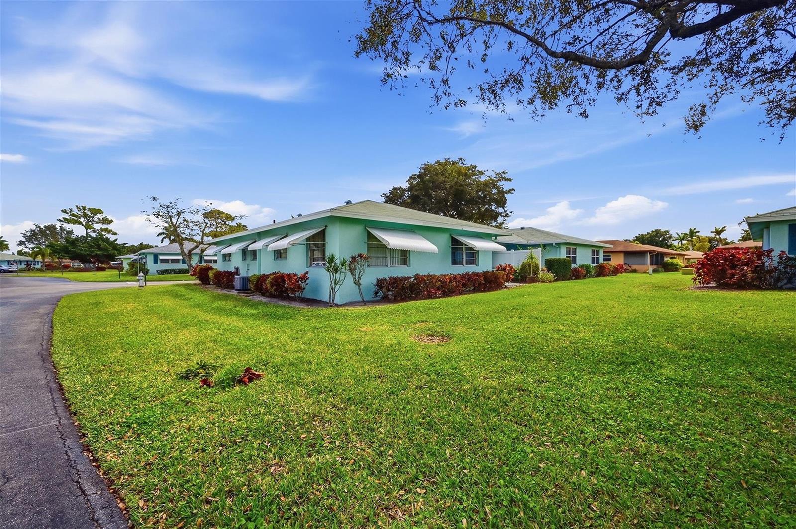 A light green single-story residential building with white awnings sits on a grassy lawn — 602 Hummingbird Lane # 602, Delray Beach FL 33445, DELRAY BEACH, FL