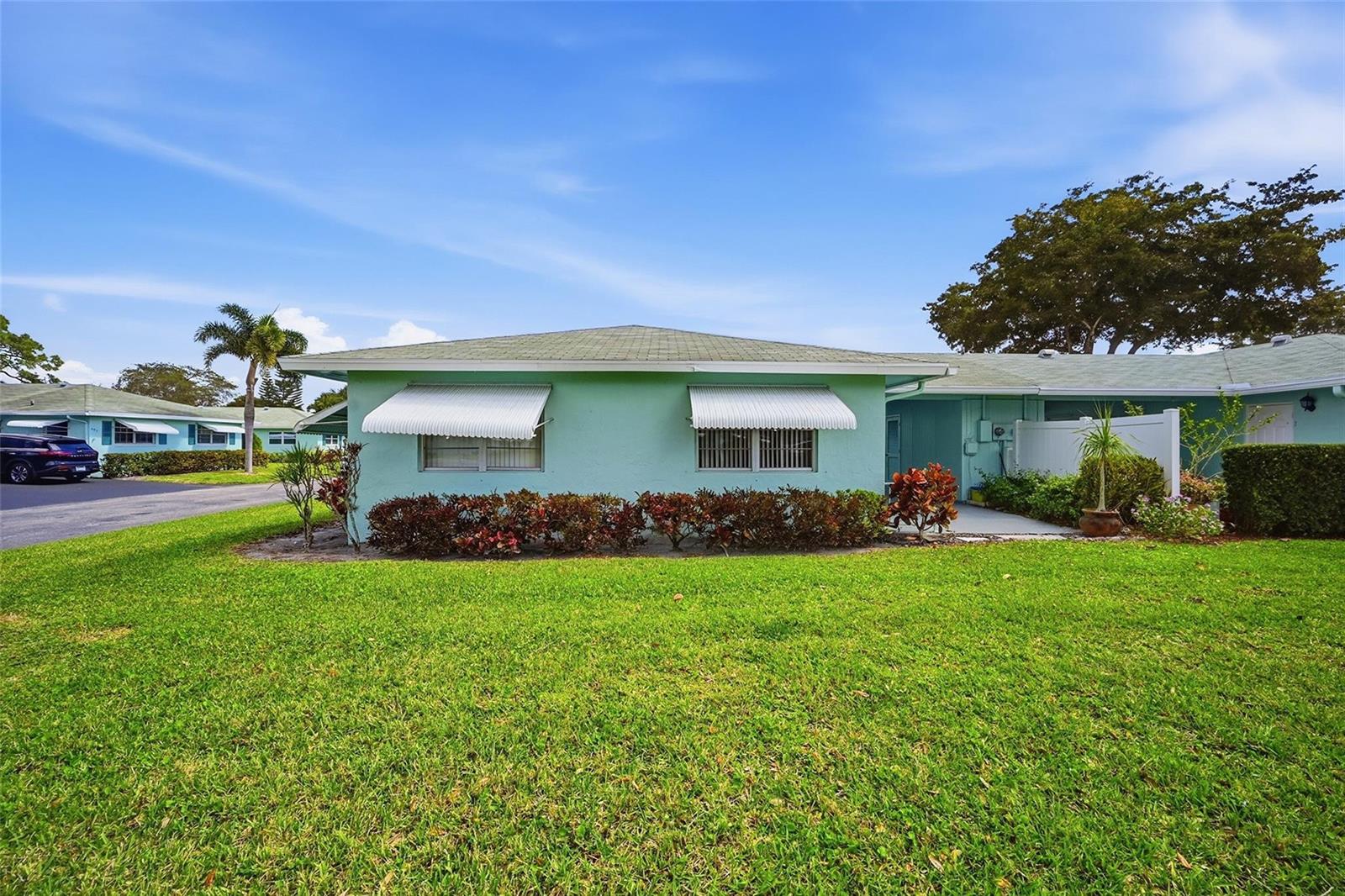 A light green single-story house features white window awnings and a manicured front lawn — 602 Hummingbird Lane # 602, Delray Beach FL 33445, DELRAY BEACH, FL