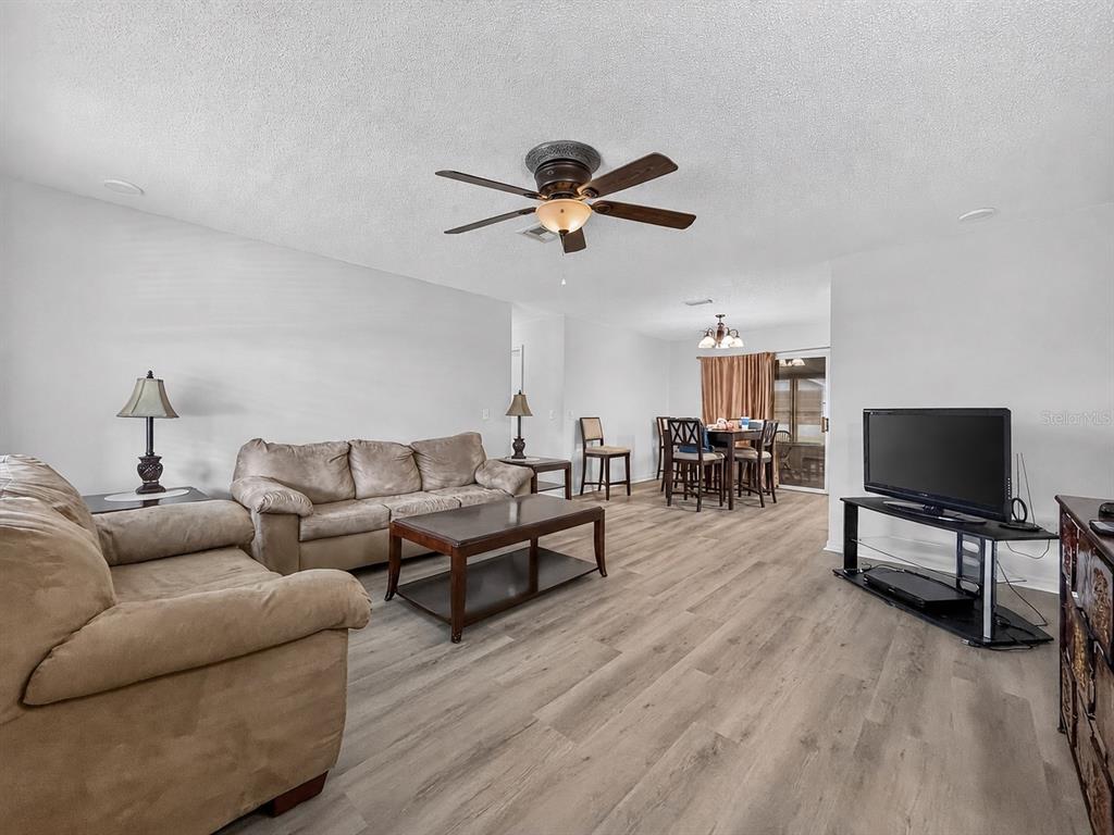 A living room features light wood-look flooring, a ceiling fan, and an adjacent dining area — 1222 SANTOS PLACE, LADY LAKE, FL