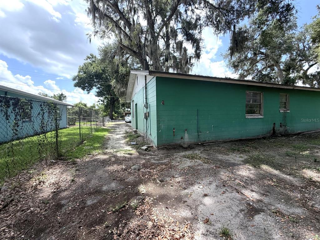 The exterior of a green, single-story building with a dirt path and surrounding trees — 14741 12TH STREET, DADE CITY, FL