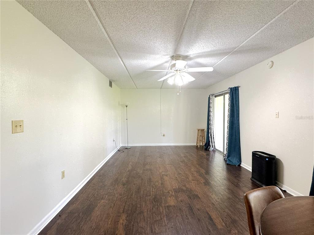 A living room with wood-look flooring, a ceiling fan, and a sliding glass door — 2400 FOREST DRIVE UNIT 139, INVERNESS, FL