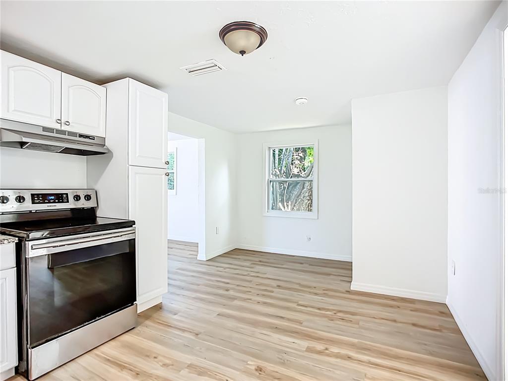 A kitchen with white cabinets, a stainless steel stove, and light wood-look flooring — 317 JESSICA STREET S, NOKOMIS, FL