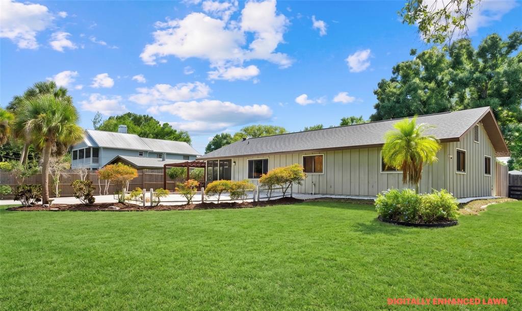 The exterior of a single-story house with vertical siding and a large green lawn — 4842 NUTMEG AVENUE, SARASOTA, FL