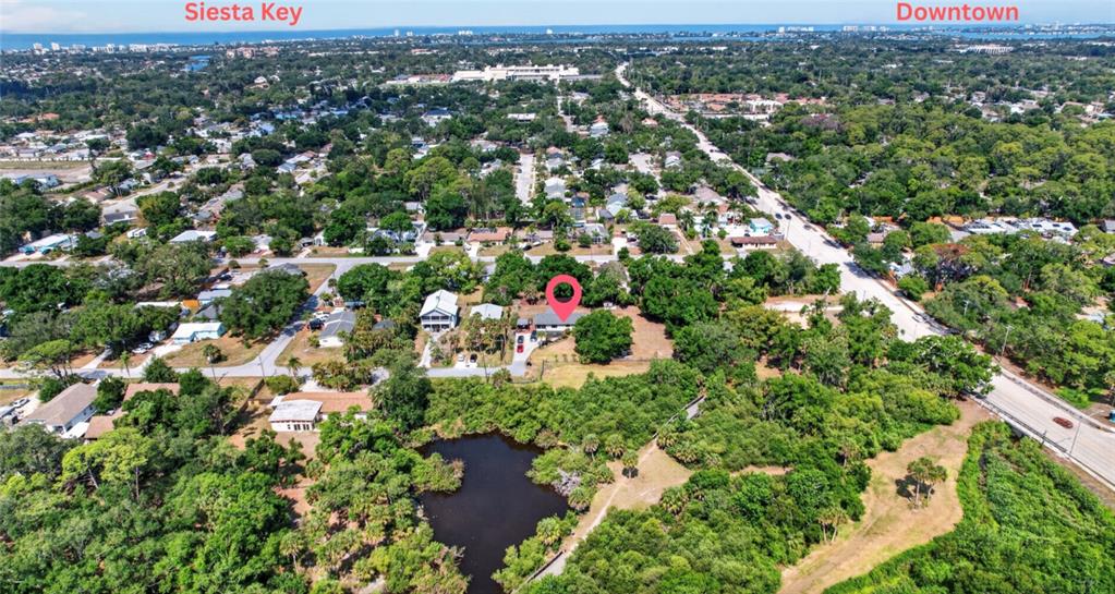 An aerial view shows a residential property with a red pin near a small pond — 4842 NUTMEG AVENUE, SARASOTA, FL