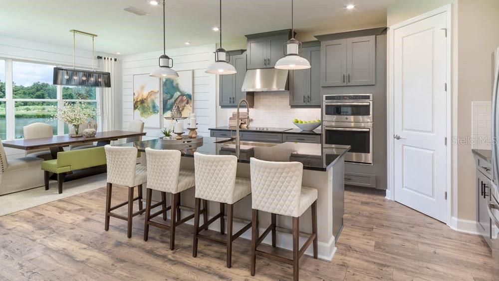 A modern kitchen features a large island with bar seating, gray cabinets, and wood flooring — 113 ARMOYAN DRIVE, PALM COAST, FL