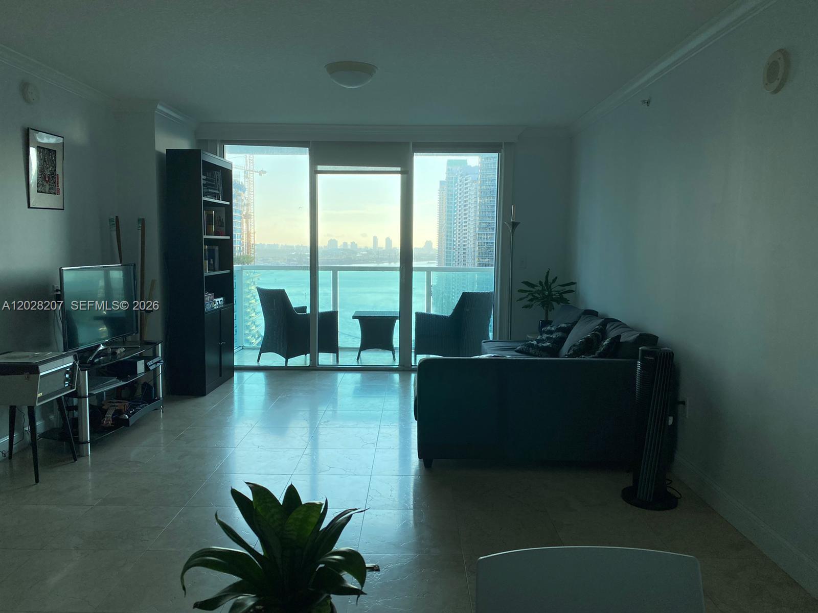A living room with tile floors, a dark sofa, and a balcony overlooking the ocean — 31 SE 5th St # 2308, Miami FL 33131, MIAMI, FL